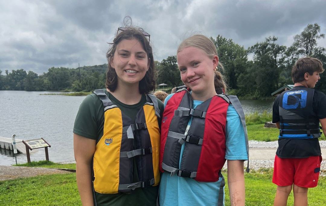 Seasonal naturalist and nature camper in life jackets by lake