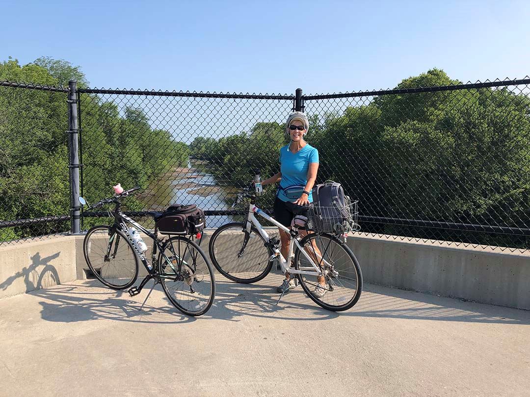 View of Skunk River from bridge on Heart of Iowa Nature Trail, cyclist posing with bicycle.