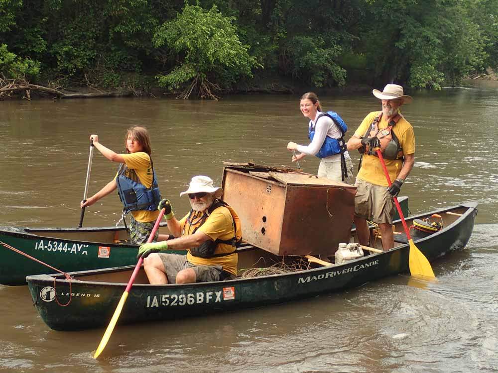 Volunteers paddle canoe in river for stream clean up