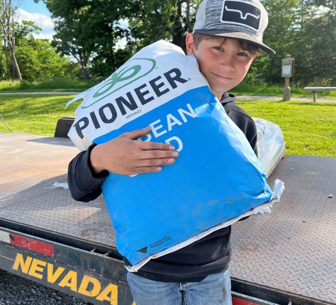 Young teen boy carries bag of Pioneer soybean seed
