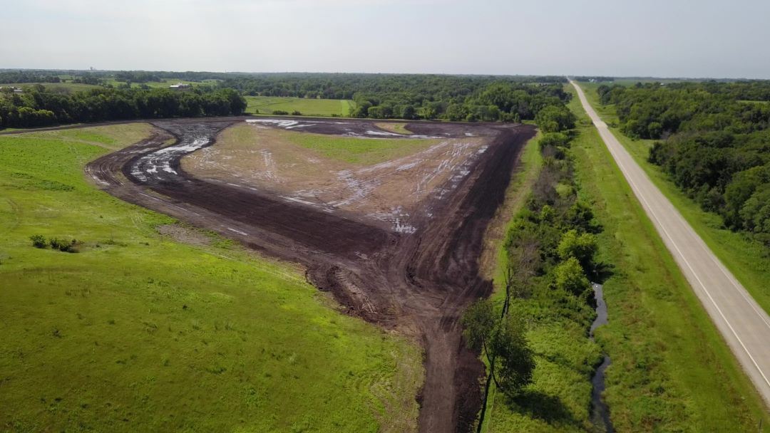 Aerial view of wetland under construction. Large, muddy pit with green