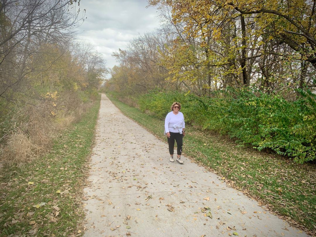 Fall foliage along paved trail with woman walking