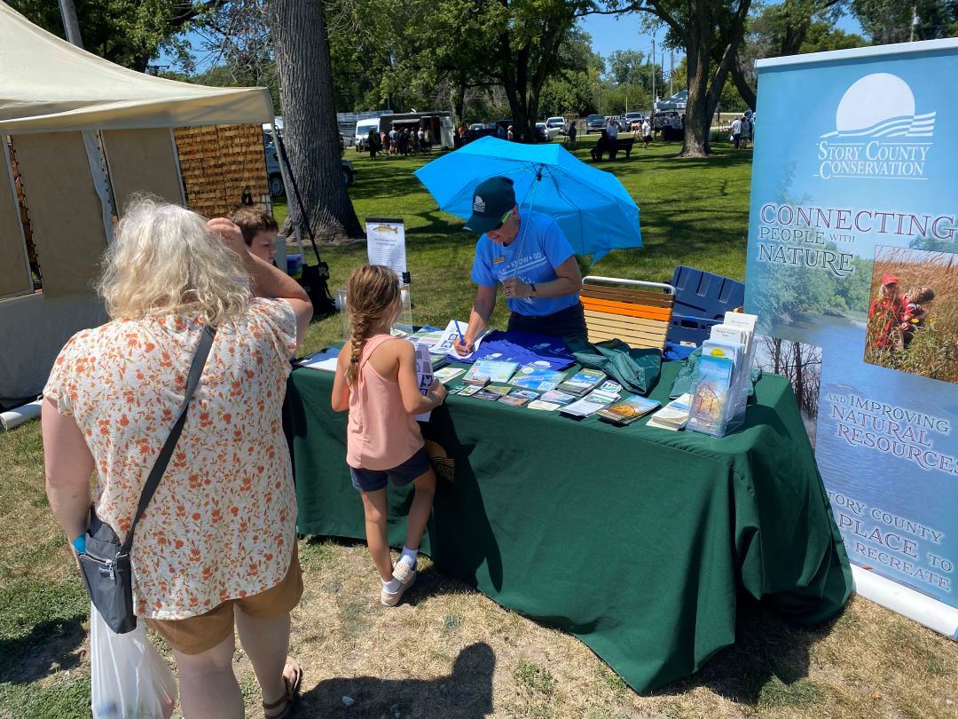 Nancy Franz shares educational material with people at outdoor summer event